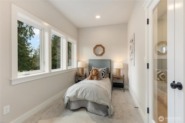 bedroom featuring light carpet, multiple windows, and baseboards