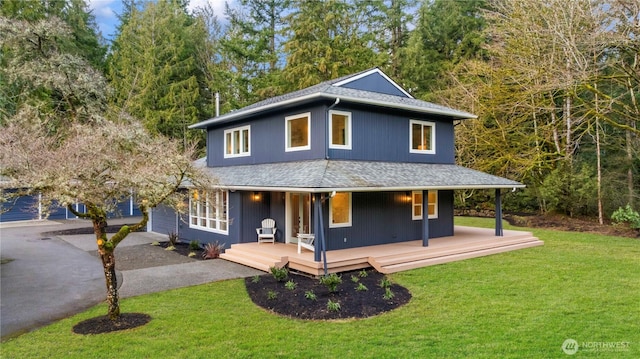 view of front of house featuring a shingled roof, a front yard, and covered porch