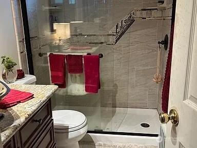 bathroom featuring vanity, toilet, and walk in shower