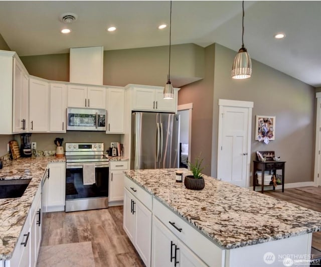 kitchen with visible vents, appliances with stainless steel finishes, a center island, white cabinetry, and pendant lighting