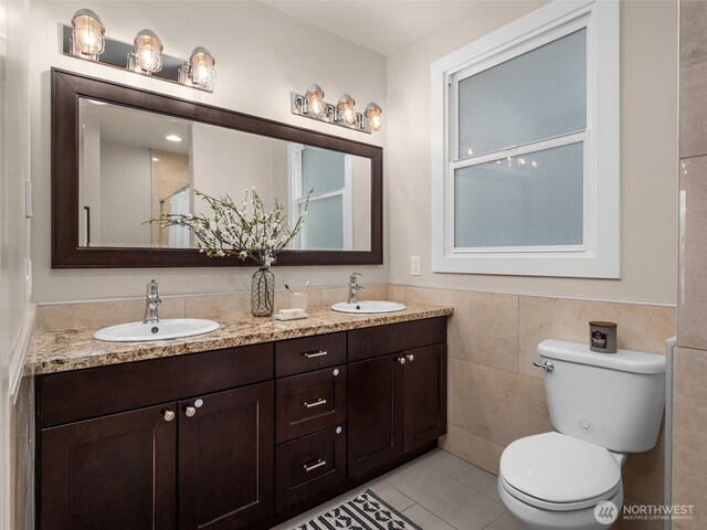 full bathroom with tile patterned flooring, a sink, tile walls, and toilet