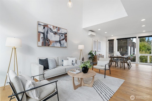 living room with a wall mounted air conditioner and light hardwood / wood-style floors