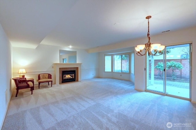 interior space with a fireplace with flush hearth, visible vents, a notable chandelier, and light colored carpet