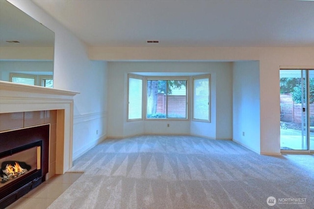 unfurnished living room with a fireplace, visible vents, and light colored carpet