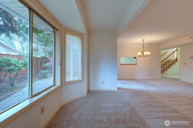 unfurnished room featuring a notable chandelier, stairway, baseboards, and light colored carpet