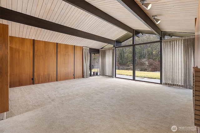 interior space featuring light carpet, wooden walls, and lofted ceiling with beams