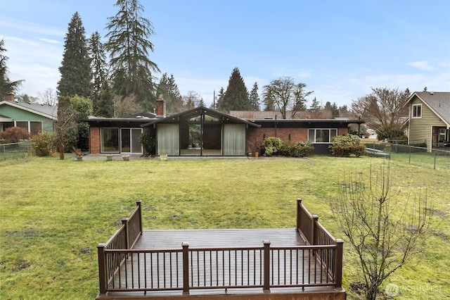 rear view of house featuring brick siding, a fenced backyard, a lawn, and a wooden deck