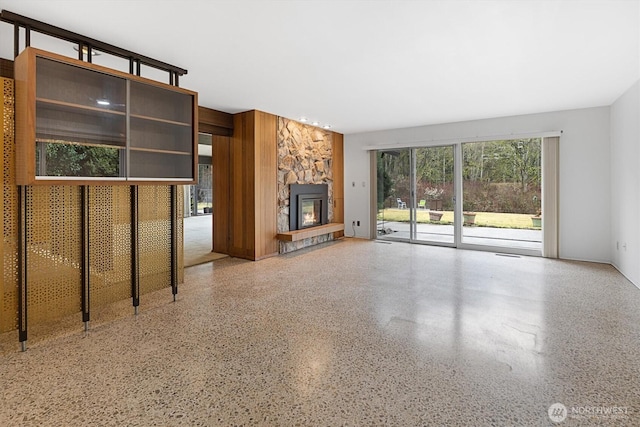 unfurnished living room with a fireplace and speckled floor