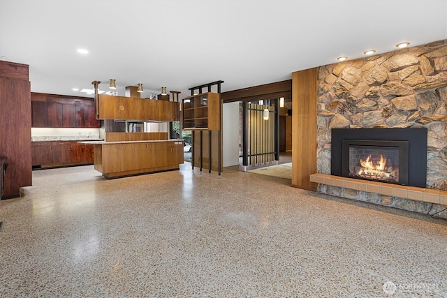 kitchen featuring light speckled floor, a fireplace, light countertops, open floor plan, and modern cabinets