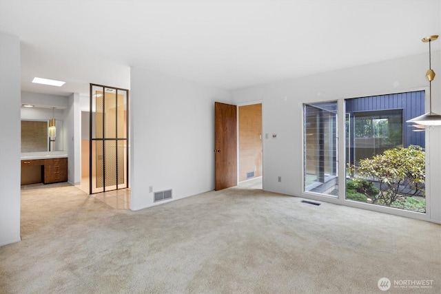 interior space with a skylight, visible vents, and light colored carpet