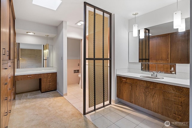 full bathroom featuring a skylight, vanity, toilet, and tile patterned floors