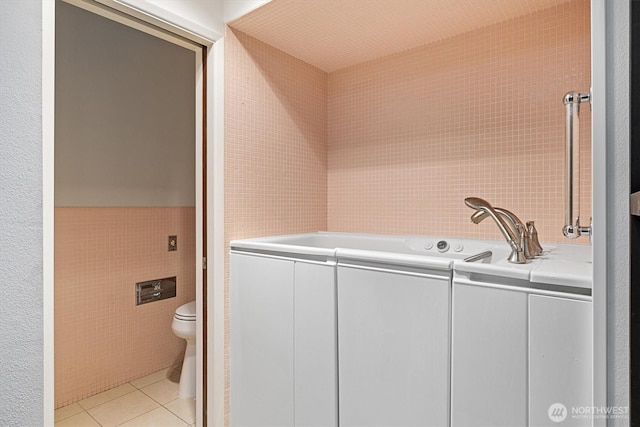 laundry room featuring light tile patterned floors and tile walls