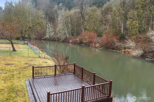 deck featuring a yard, a water view, and fence