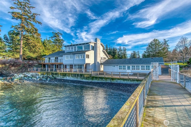 rear view of house featuring a chimney and a water view