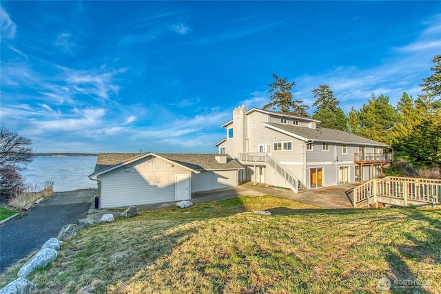 rear view of house with stairs, a lawn, and a deck with water view