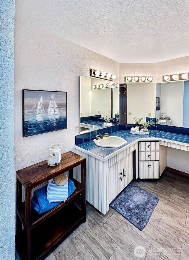 bathroom with a textured ceiling, a textured wall, vanity, and wood tiled floor