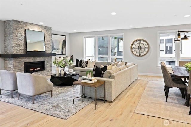 living room featuring a stone fireplace and light hardwood / wood-style flooring