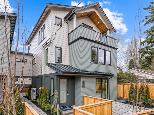 rear view of property with a standing seam roof, fence, and metal roof