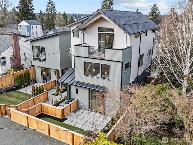 view of front of property with metal roof, a standing seam roof, a fenced backyard, and a balcony