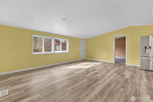 unfurnished living room with vaulted ceiling, light wood-style flooring, visible vents, and baseboards