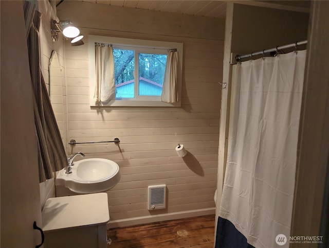 bathroom featuring sink, wood-type flooring, and wooden walls