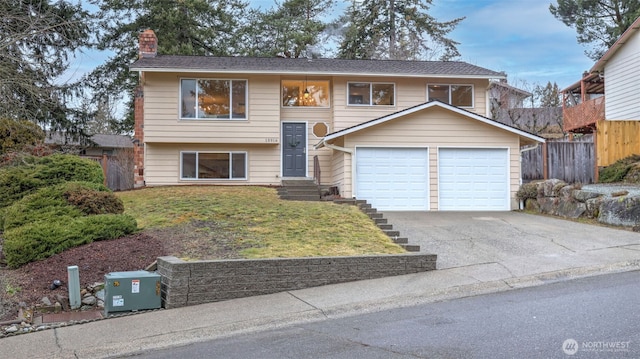 split foyer home with driveway, a chimney, a front yard, and fence