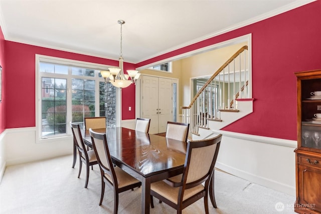 dining area with stairs, light colored carpet, ornamental molding, and an inviting chandelier