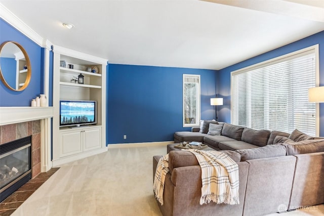 living room with built in shelves, a tile fireplace, carpet flooring, and baseboards