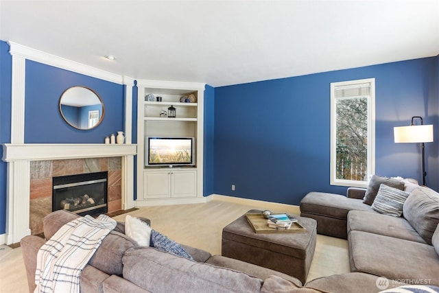 living area with built in shelves, light colored carpet, a fireplace, and baseboards