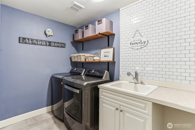 washroom featuring light tile patterned floors, visible vents, washing machine and dryer, a sink, and baseboards