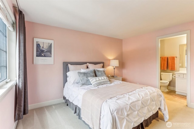 bedroom featuring light carpet, connected bathroom, and baseboards