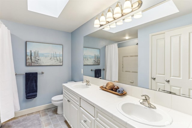 bathroom with double vanity, a skylight, a sink, and toilet