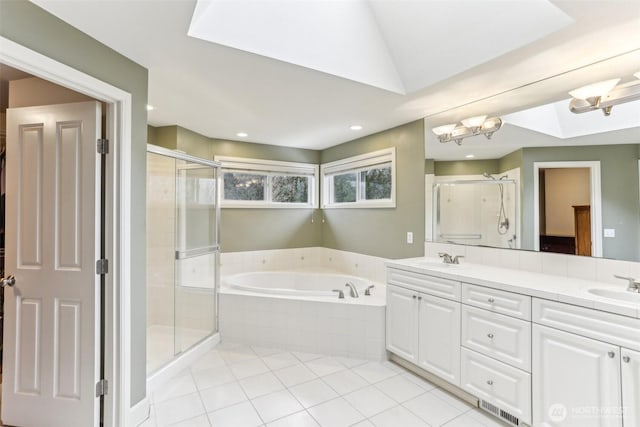 bathroom with a garden tub, double vanity, a stall shower, a sink, and tile patterned flooring