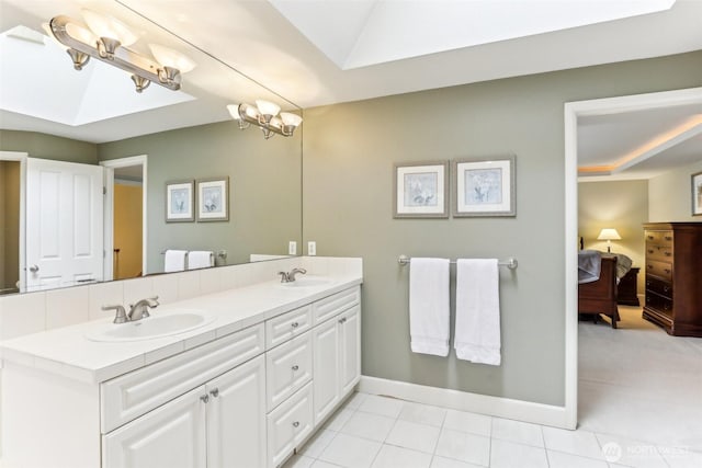 ensuite bathroom with double vanity, ensuite bath, baseboards, and a sink