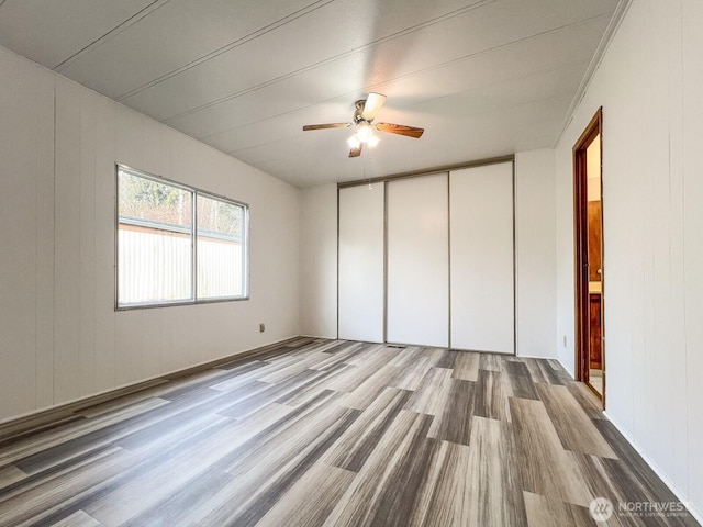 unfurnished bedroom featuring ceiling fan, a closet, and light wood-style flooring