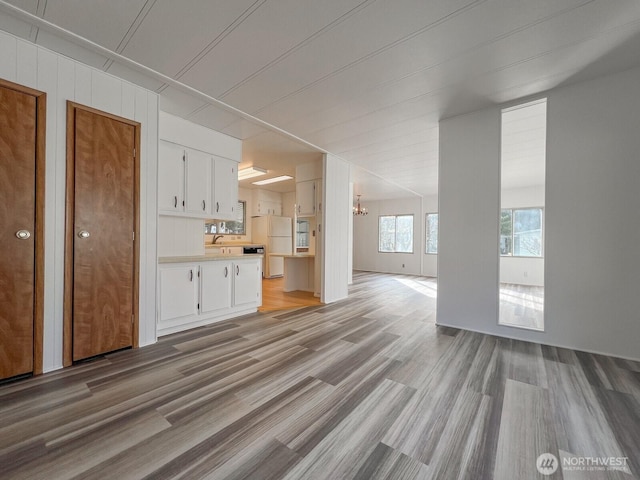 unfurnished living room with light wood-style floors and a notable chandelier