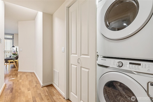 laundry room with stacked washing maching and dryer and light wood-type flooring