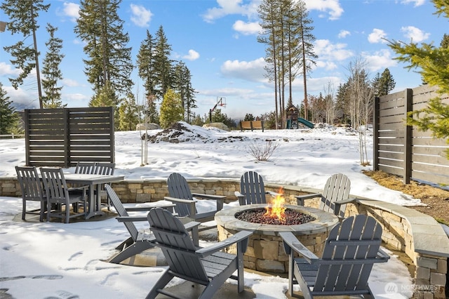 snow covered patio featuring fence and a fire pit