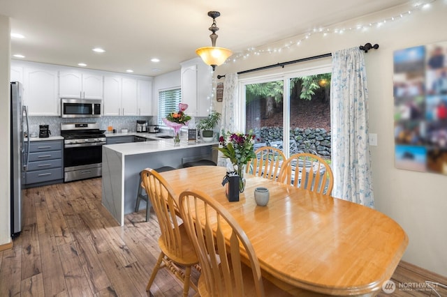 interior space with a peninsula, white cabinets, appliances with stainless steel finishes, backsplash, and decorative light fixtures