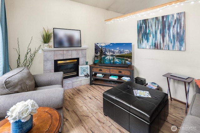 living room with a tiled fireplace and wood finished floors