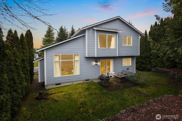 back of house at dusk with a yard, an outdoor fire pit, crawl space, and a patio