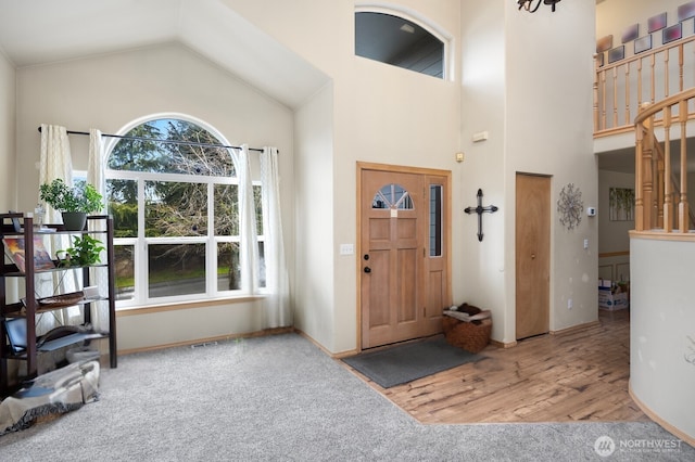 carpeted foyer entrance featuring plenty of natural light and high vaulted ceiling