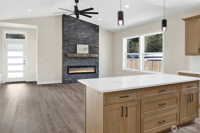 kitchen featuring lofted ceiling, light stone countertops, a fireplace, and decorative light fixtures