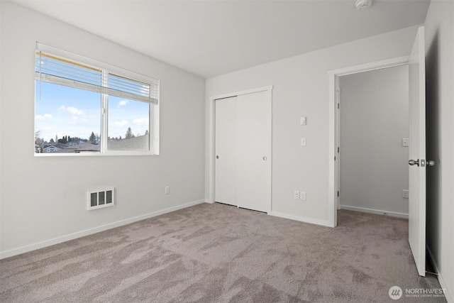 unfurnished bedroom featuring light carpet, baseboards, visible vents, and a closet