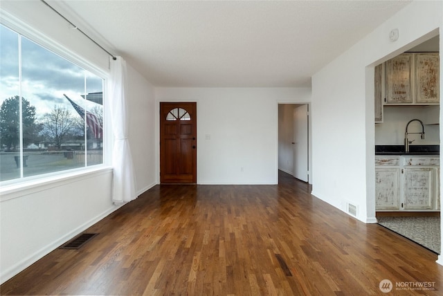 interior space with dark wood finished floors, visible vents, and baseboards