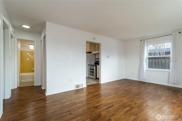 unfurnished room with a textured ceiling, dark wood-type flooring, visible vents, and baseboards