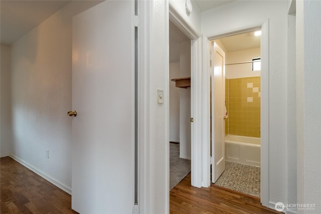 hallway featuring baseboards and wood finished floors