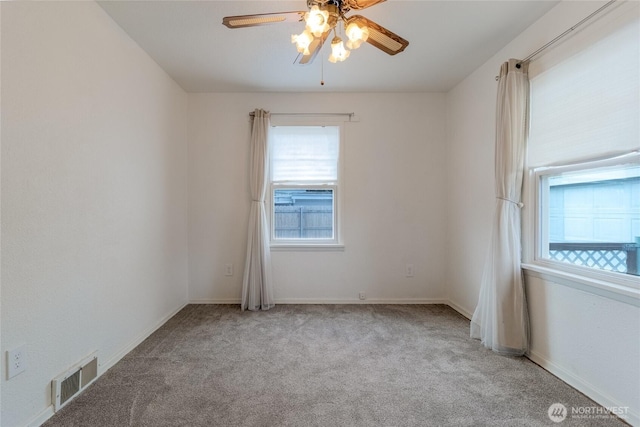 unfurnished room featuring a ceiling fan, light colored carpet, visible vents, and baseboards