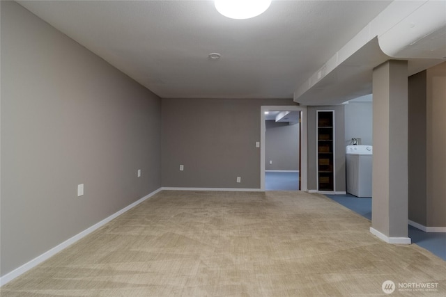 spare room featuring baseboards, washer / dryer, and light colored carpet