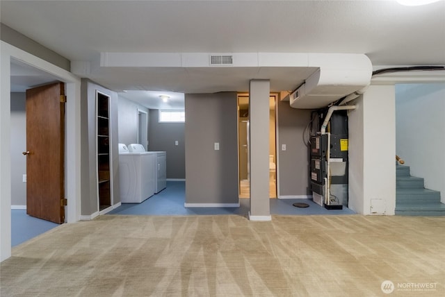 below grade area with visible vents, light colored carpet, heating unit, stairs, and washing machine and dryer